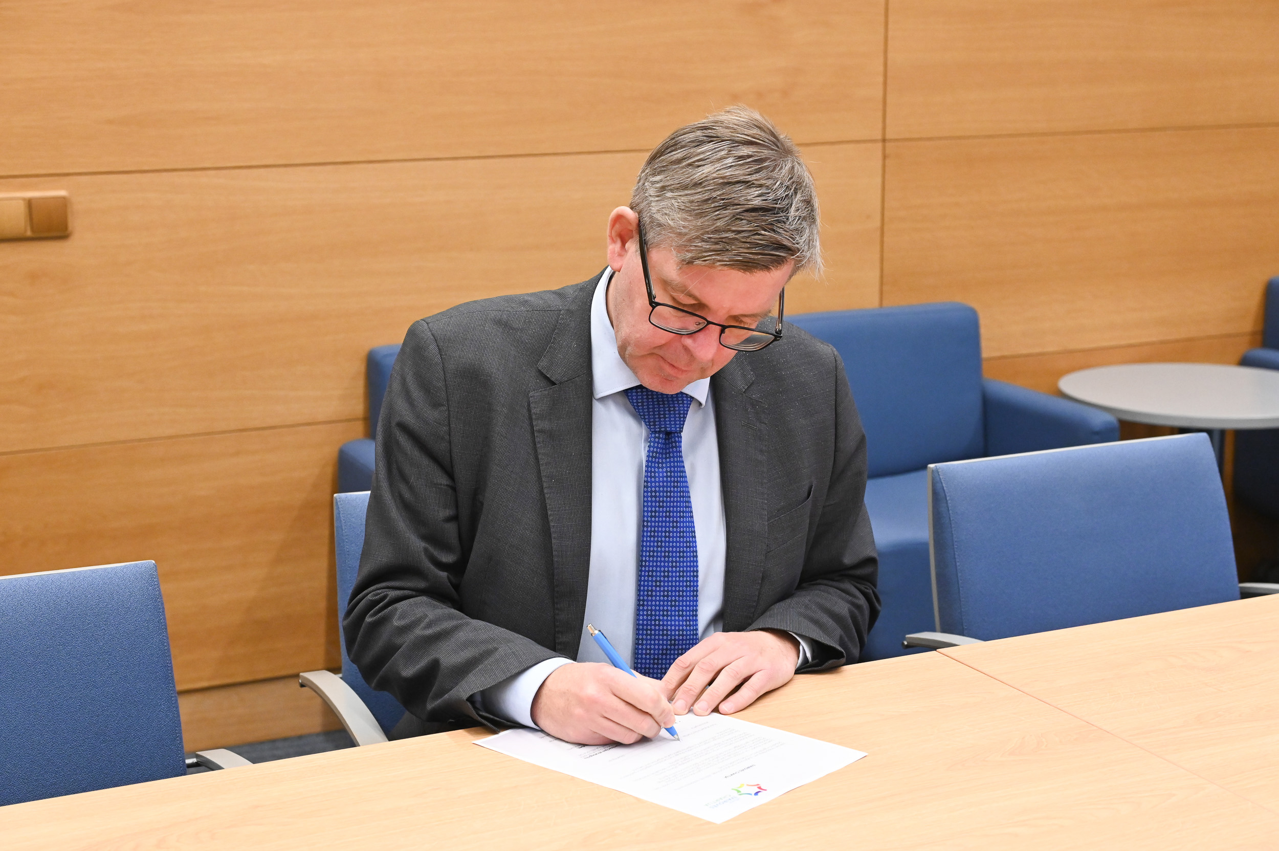 Vyras pasirašo dokumentą 2